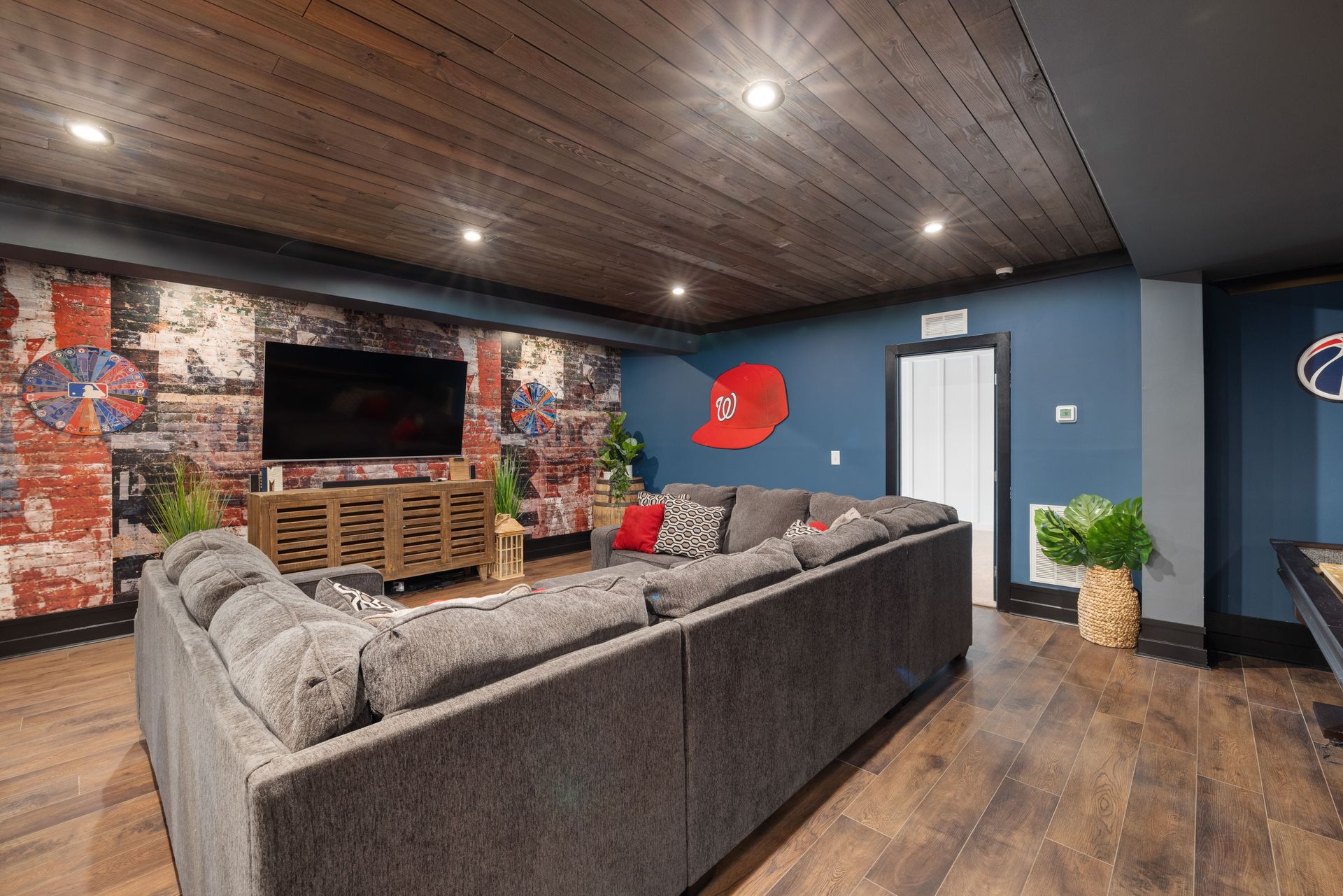 Spacious basement room featuring stylish decor, large couch, and TV setup.
