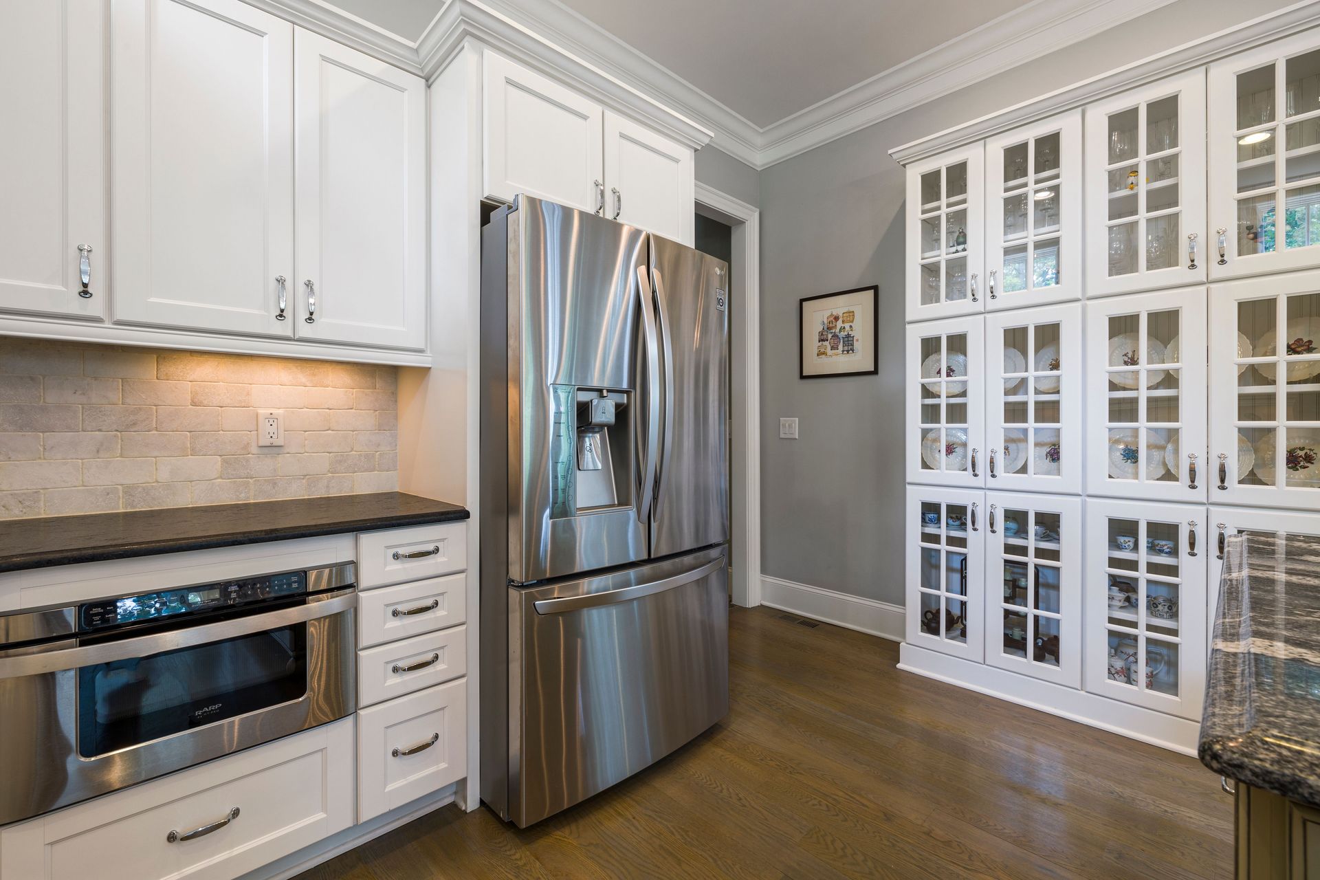 Contemporary kitchen interior featuring stainless steel fridge and white cabinets.